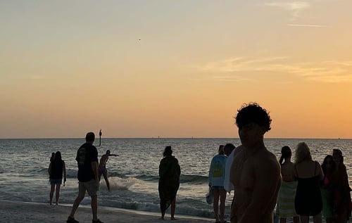 Ein Strand in Florida bei Sonnenuntergang und mehreren Silhouetten vor dem Meer