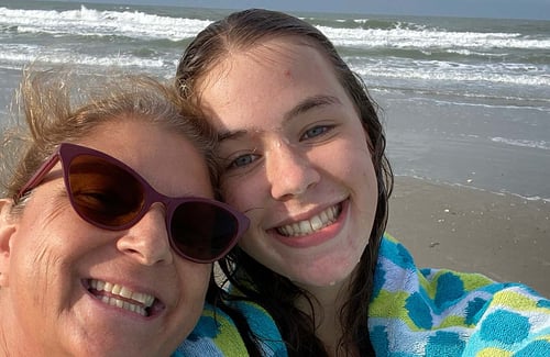 Schülerin und Gastmutter lächelnd am Strand und hinter ihnen das Meer