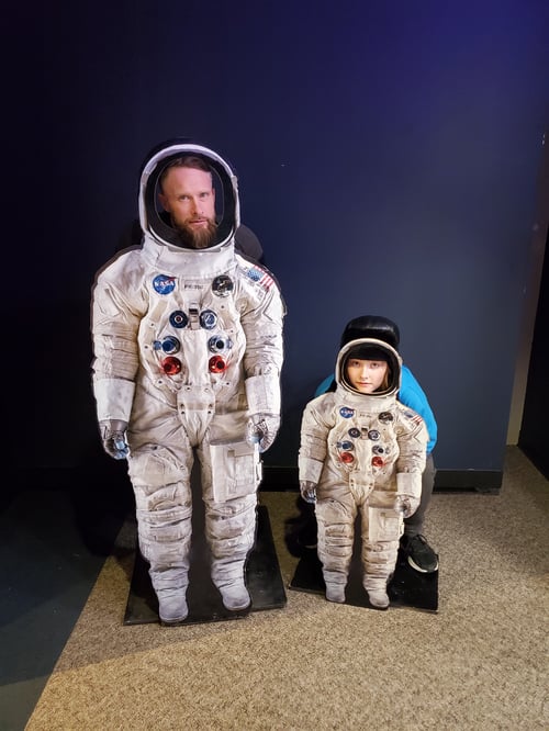 Zwei Menschen stehen hinter Astronauten aus Pappe