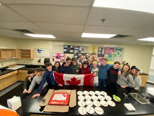 Gruppe von Schülern mit Kanada Flagge und Kuchen auf einem Tisch