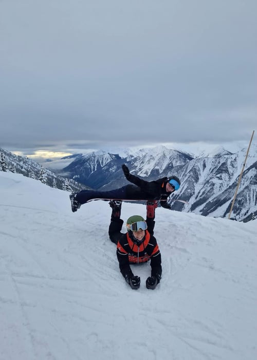 Zwei Menschen mit Snowboard auf einer Skipiste