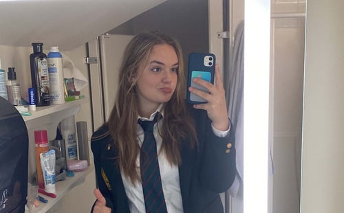 Eine Schülerin in Schuluniform im Badezimmer vor dem Spiegel