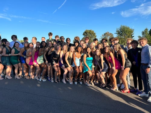 Eine große Gruppe an Jugendlichen in Kleidern und Anzügen