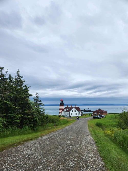 Eine Straße mit Meer und Leuchtturm im Hintergrund