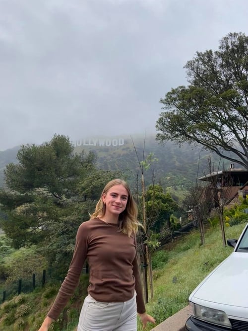 Mädchen vor grüner Landschaft und dem Hollywood Zeichen