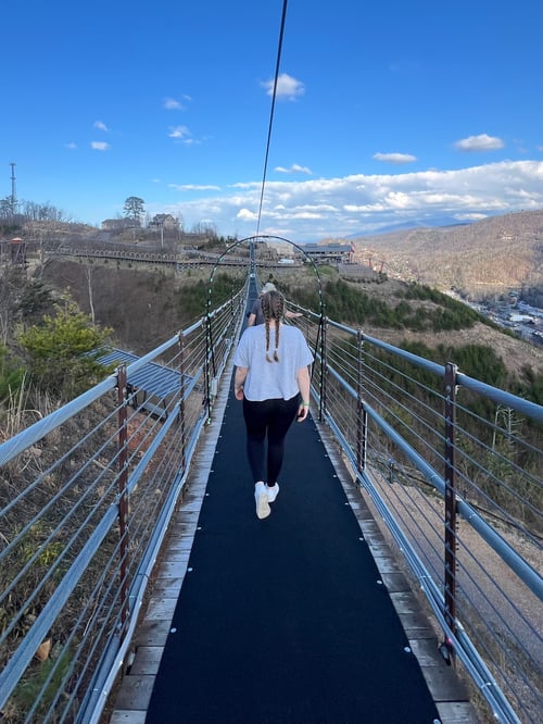 Ein Mädchen auf einer Brücke über den Bergen