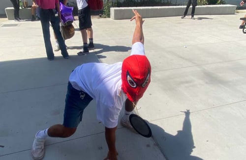 Ein Kind mit Spiderman Maske posiert auf dem Asphalt