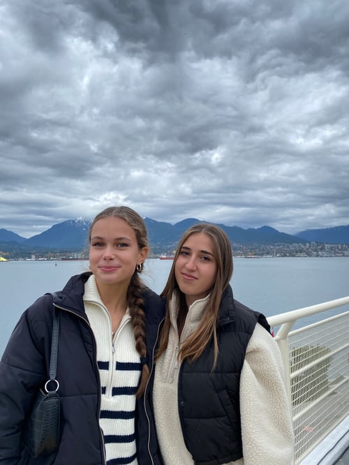Zwei Mädchen auf einem Schiff mit Meer und Bergen im Hintergrund