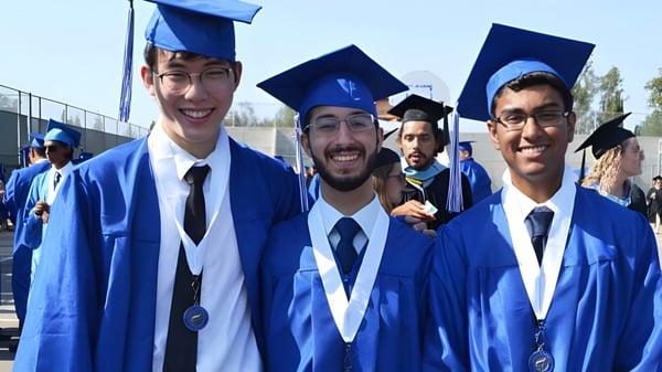 Eine Gruppe von Absolventinnen und Absolventen der A.B. Lucas Secondary School feiert im Freien ihre akademischen Erfolge in blauen Talaren.