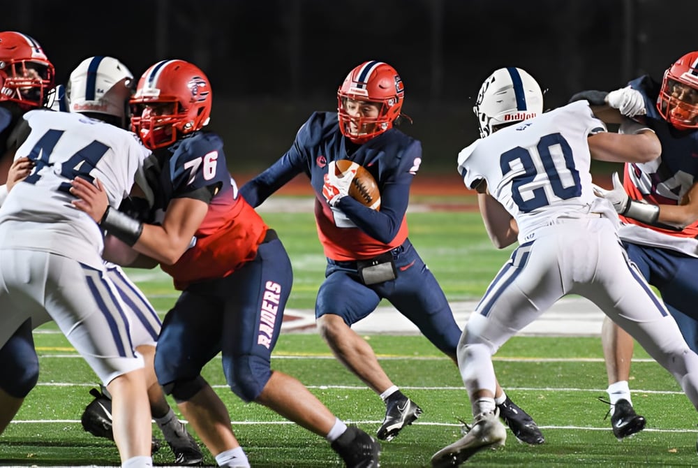 Eine Gruppe von Football-Spielern der A.B. Lucas Secondary School spielt ein Spiel auf dem Fußballfeld bei Nacht.