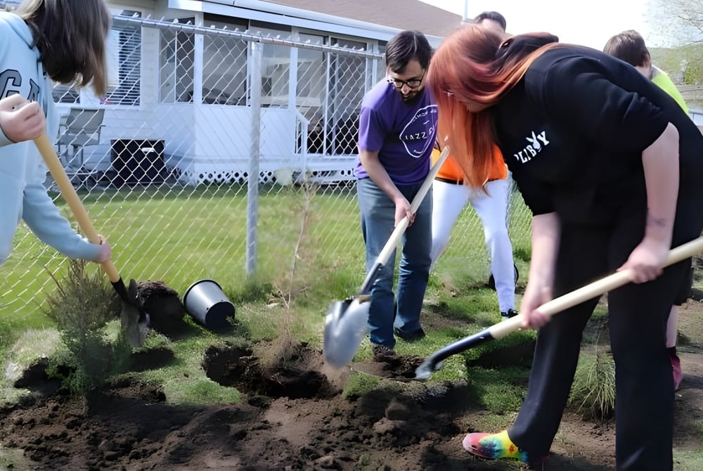 Schüler der A.L. Fortune Secondary School graben gemeinsam Löcher im Boden für eine Pflanzaktion im Freien.