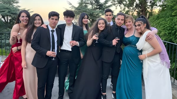 Eine Gruppe Schüler des Abbey College posiert formell im Freien vor Bäumen und Grünfläche.