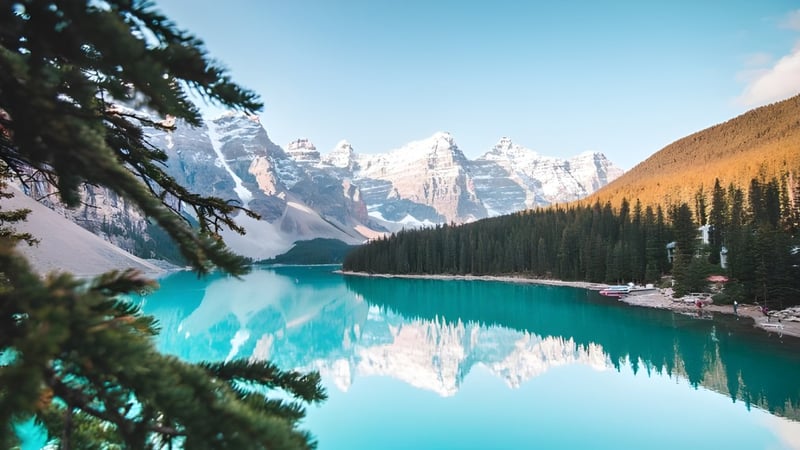 Ein klarer alpiner See mit schneebedeckten Bergen und einem Wald im Vordergrund nahe der Abbey Park High School.