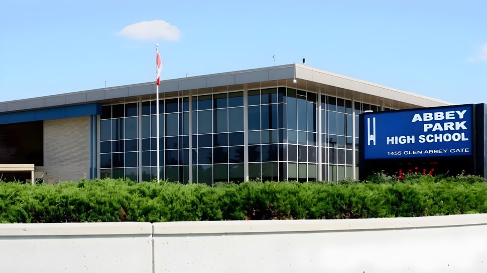 Das moderne Schulgebäude der Abbey Park High School mit Glasfront ist von grüner Vegetation umgeben.