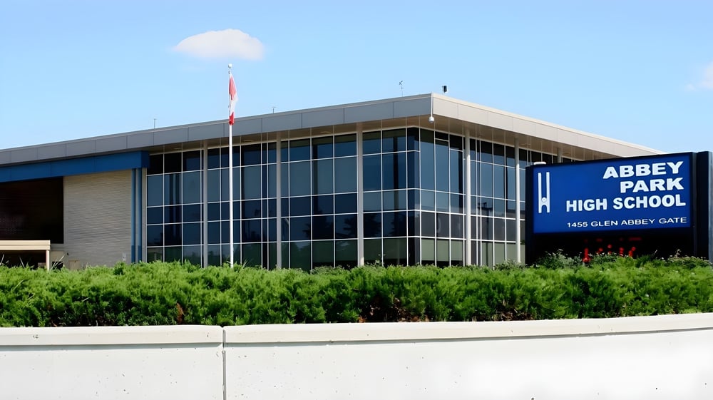 Das moderne Schulgebäude der Abbey Park High School mit Glasfront ist von grüner Vegetation umgeben.