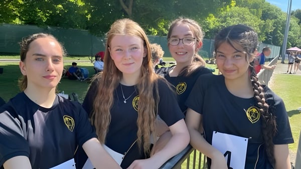 Vier Schülerinnen der Abbey Park High School stehen zusammen auf einer Wiese im Freien.