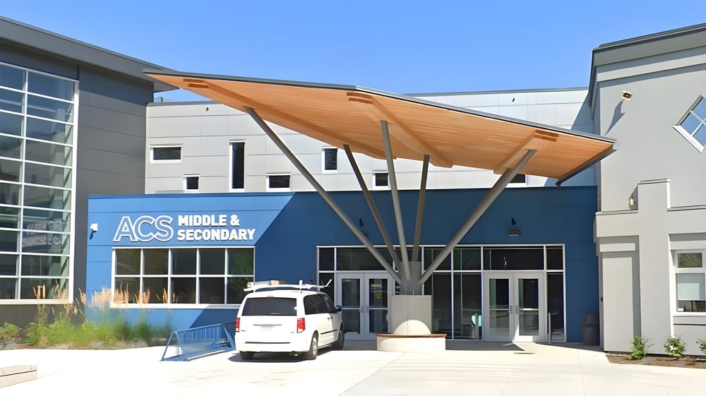 Das moderne mehrstöckige Gebäude der Abbotsford Christian School mit blauem Außenanstrich und hölzernem Vordach am Eingang.