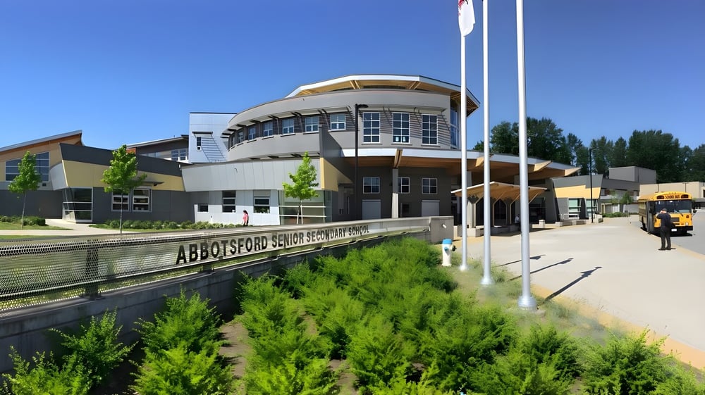 Das moderne mehrstöckige Gebäude mit einem geschwungenen Dach der Abbotsford Senior Secondary School steht in einer begrünten Umgebung.