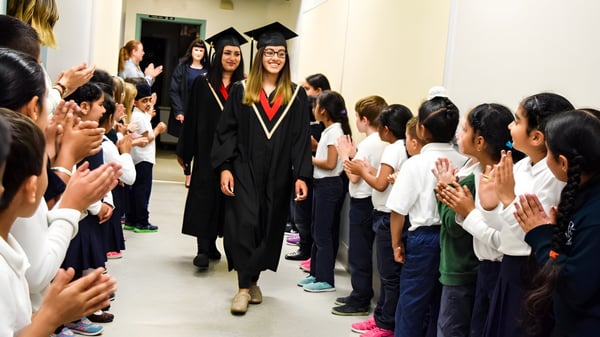 Absolventen der Abbotsford Traditional Secondary School gehen in ihren Talaren durch einen Flur voller jubelnder Schüler.