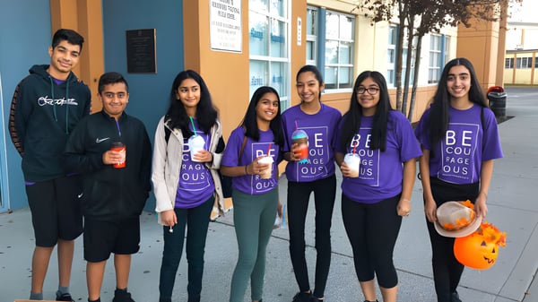 Eine Gruppe von Schülerinnen und Schülern vor dem farbenfrohen Gebäude der Abbotsford Traditional Secondary School.