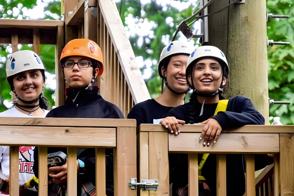 Schüler der Abbotsford Traditional Secondary School stehen mit Schutzhelmen und Sicherheitskleidung auf einer Holzplattform im Grünen.