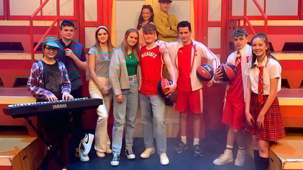 Eine Gruppe Schüler steht zusammen vor einem rot-orangenen Hintergrund auf dem Campus der Abbotsholme School.