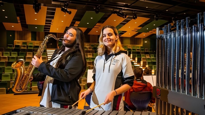 Zwei Personen stehen in einem Musikraum auf dem Campus der Aberfoyle Park High School mit bunter Beleuchtung und Musikausstattung im Hintergrund.