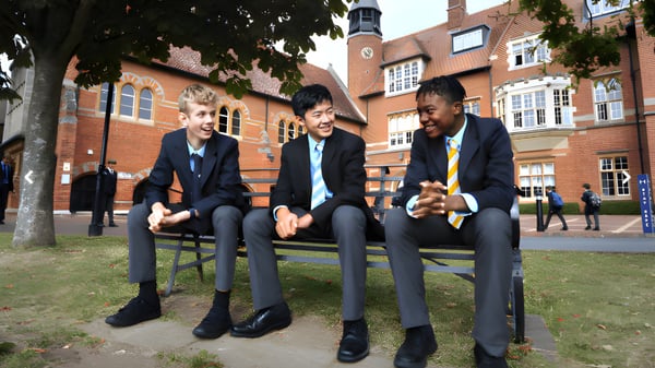 Drei Schüler der Abingdon School sitzen auf Bänken im Innenhof zwischen Backsteingebäuden.