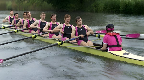 Das Ruderteam der Abingdon School trainiert auf einem Fluss umgeben von grüner Vegetation.