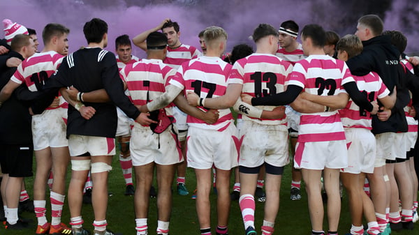 Eine Gruppe Rugby-Spieler im pink-weiß gestreiften Trikot steht in einer Huddle auf dem Feld der Abingdon School.