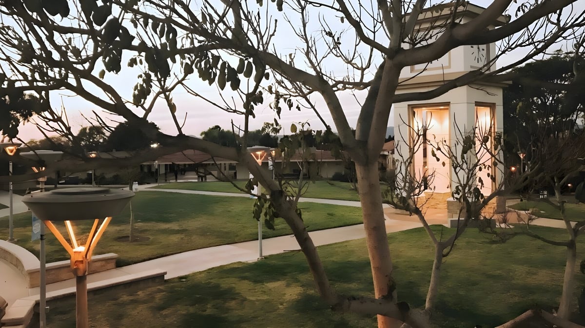 Der Außenbereich mit Terrasse und grünem Rasen auf dem Campus der Academy MiraCosta ist von Gebäuden und kahlen Bäumen umgeben.