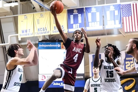 Basketballspiel mit Spielern der Academy of the New Church in einer Sporthalle mit amerikanischen Flaggen.