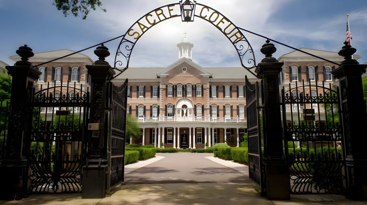 Ein verzierte schmiedeeiserne Pforte führt zu einem mehrstöckigen Backsteingebäude mit Kuppel auf dem Campus der Academy of the Sacred Heart.