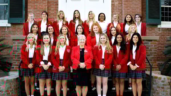 Eine Gruppe Schülerinnen in roten Uniformen steht vor einem Backstein-Gebäude auf dem Campus der Academy of the Sacred Heart.