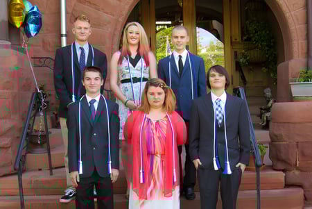 Eine Gruppe von Absolventinnen und Absolventen steht vor dem Backsteingebäude der Accelerated School.