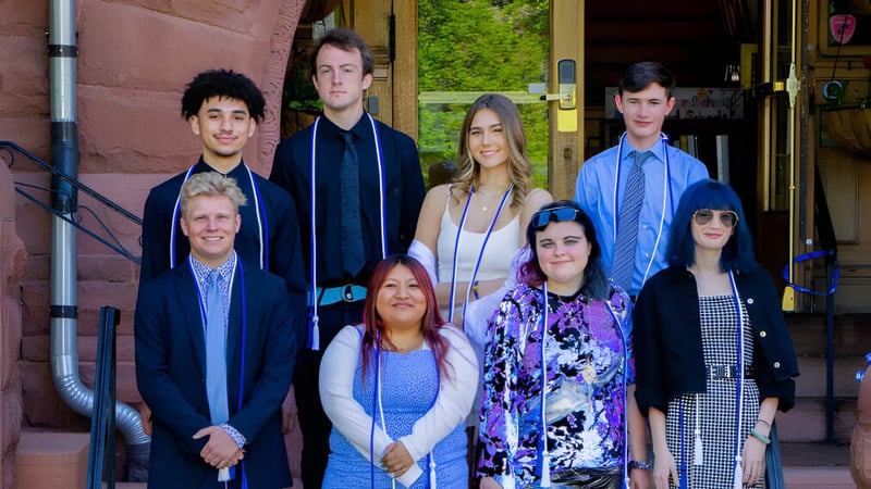 Eine Gruppe von Schülerinnen und Schülern steht vor einem Backsteingebäude auf dem Campus der Accelerated School.