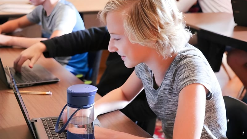 Eine Schülerin der Accelerated School arbeitet konzentriert an einem Laptop im Klassenzimmer mit anderen Schülern.