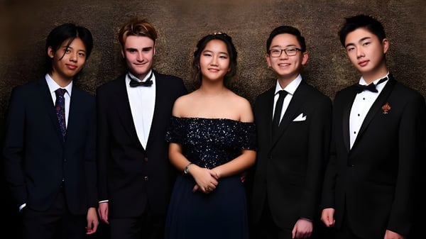 Eine Gruppe von fünf Personen in formeller Kleidung posiert auf dem Campus des ACG Parnell College vor dunklem Hintergrund.