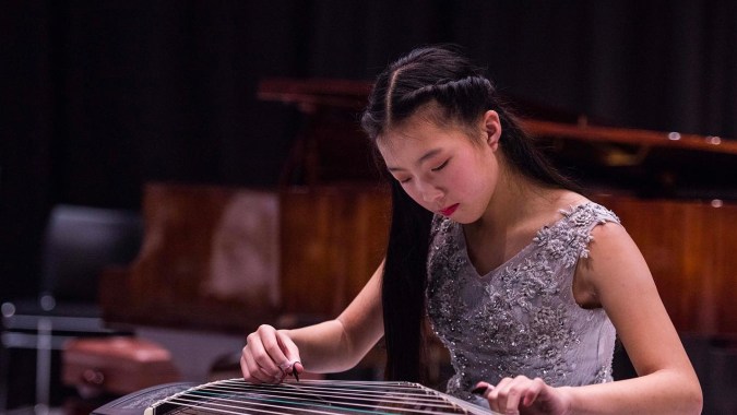 Eine Schülerin des ACG Parnell College spielt konzentriert ein traditionelles chinesisches Instrument auf einer Bühne.