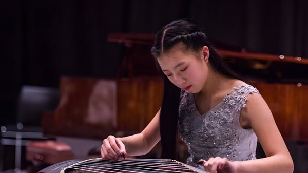 Eine Schülerin des ACG Parnell College spielt konzentriert ein Musikinstrument auf einer Bühnenbeleuchtung.