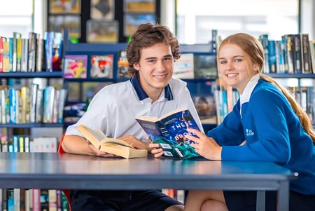 Zwei Schüler der ACG Strathallan sitzen gemeinsam an einem Tisch in der Bibliothek und lesen Bücher.