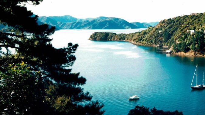 Ein ruhiger See mit einem Boot und bewaldeten Bergen auf dem Gelände von ACG Strathallan.