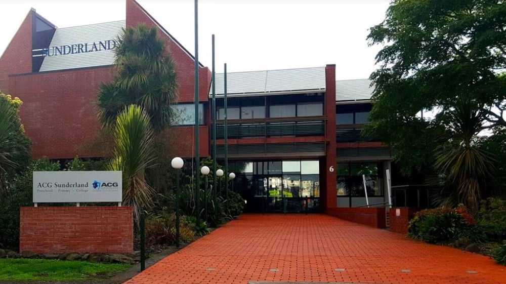 Das rote Backsteingebäude mit dem Schriftzug NEDERLAND auf dem grünen Campus der ACG Sunderland.