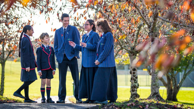Schüler der ACG Sunderland stehen gemeinsam in einem herbstlichen Außenbereich mit buntem Laub im Hintergrund.