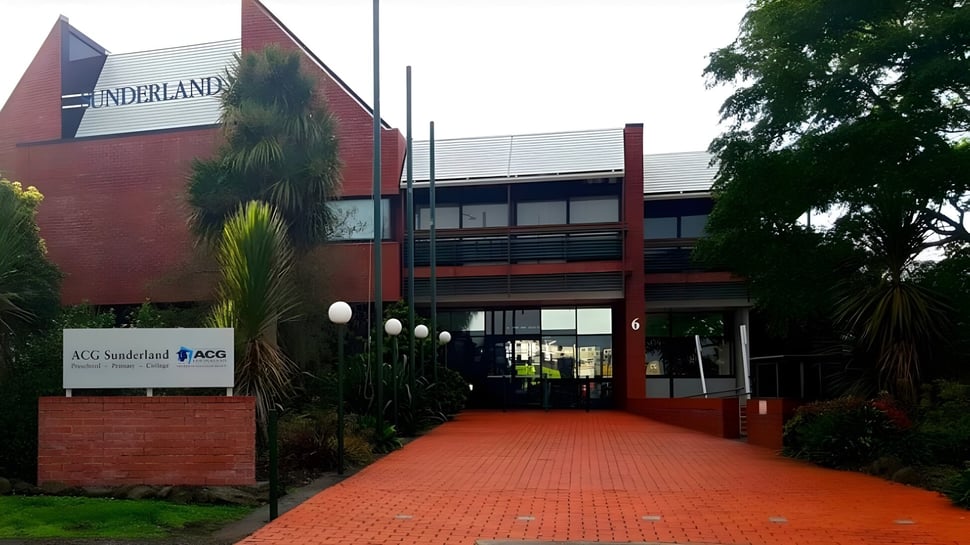Das rote Backsteingebäude mit dem Schriftzug ACG Sunderland ist von Bäumen umgeben und über einen gepflasterten Weg zugänglich.