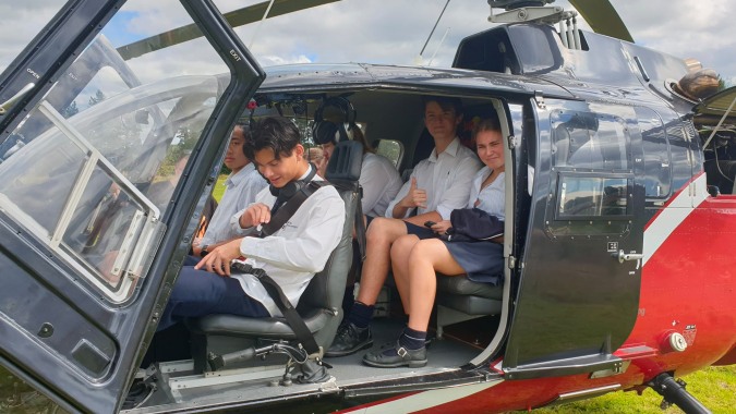 Zwei Personen sitzen im Inneren eines Hubschraubers auf dem Campus der ACG Tauranga.