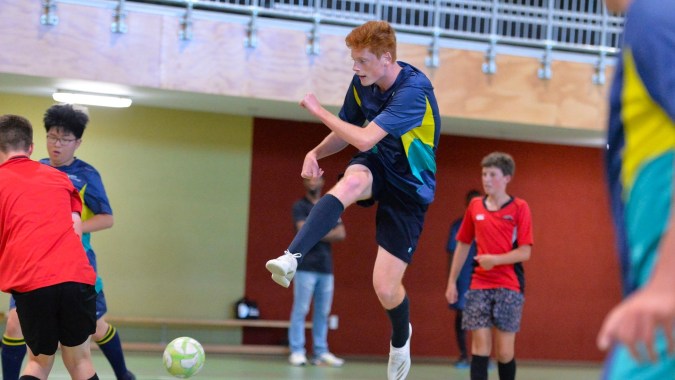 Schüler der ACG Tauranga spielen in einer Halle eine Bewegungsspiel mit bunten Trikots.