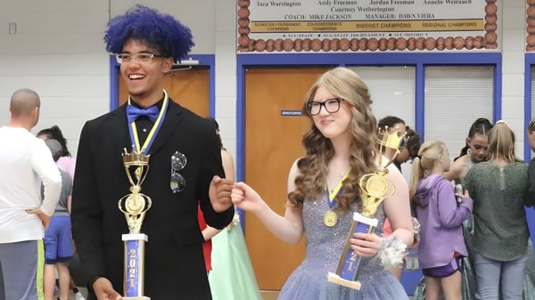 Zwei Schülerinnen und Schüler der Acorn High School halten Trophäen bei einer Siegerehrung in der Schule.