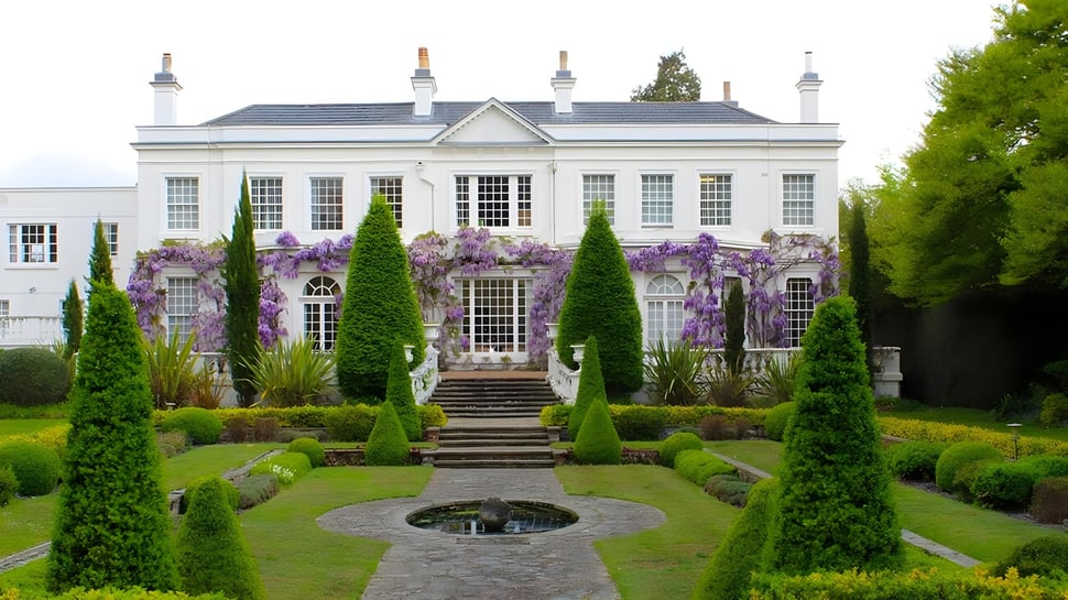 Das weiße Herrenhaus mit symmetrischer Fassade und einer blühenden Glyzinie im Garten der ACS International School Cobham.
