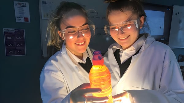Zwei Schüler der Adcote School im Labor halten ein leuchtendes gelbes Objekt während des Experiments.